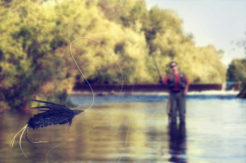 trout fly attached to leader and fly line being cast in river